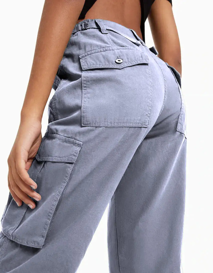 Close-up back view of blue cargo trousers showcasing rear and side pockets with button flap closures.