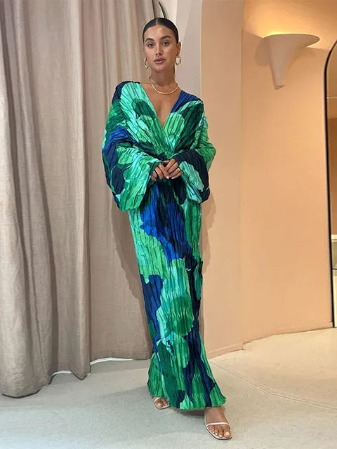 "Elegant long-sleeve pleated maxi dress with a bold green and blue abstract floral print, featuring a deep V-neckline and relaxed fit."
