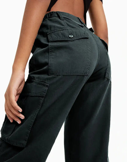 Close-up back view of black cargo trousers highlighting flap pockets and structured stitching.