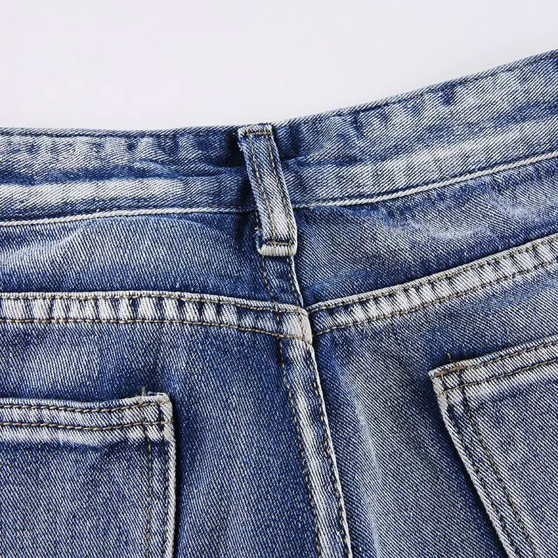 Close-up of back waistband seam and belt loop on faded blue jeans.