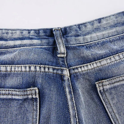 Close-up of back waistband seam and belt loop on faded blue jeans.