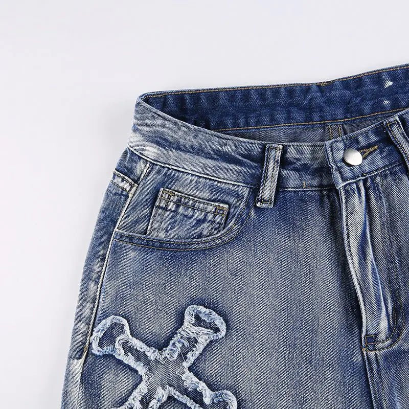 Close-up of the front waistband and pocket stitching on distressed denim jeans.