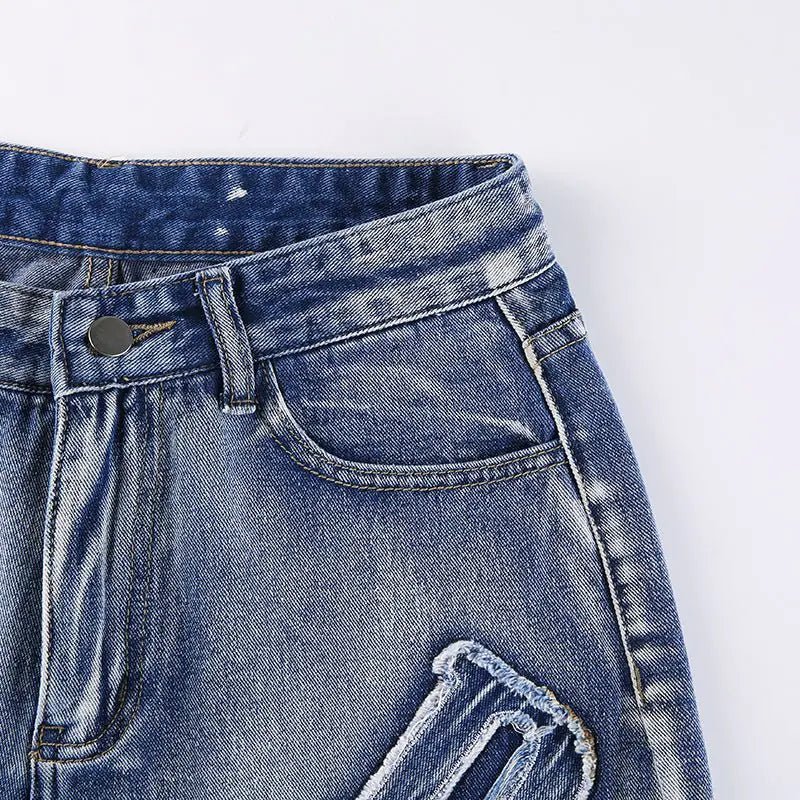 Close-up of the front waistband and pocket stitching on distressed denim jeans.