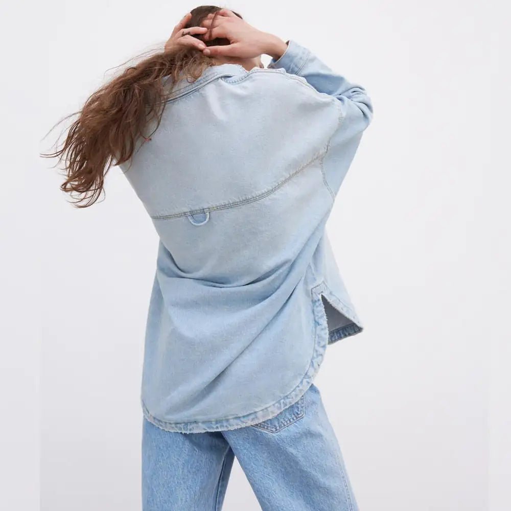 Back view of oversized light blue denim shirt jacket with curved hem.
