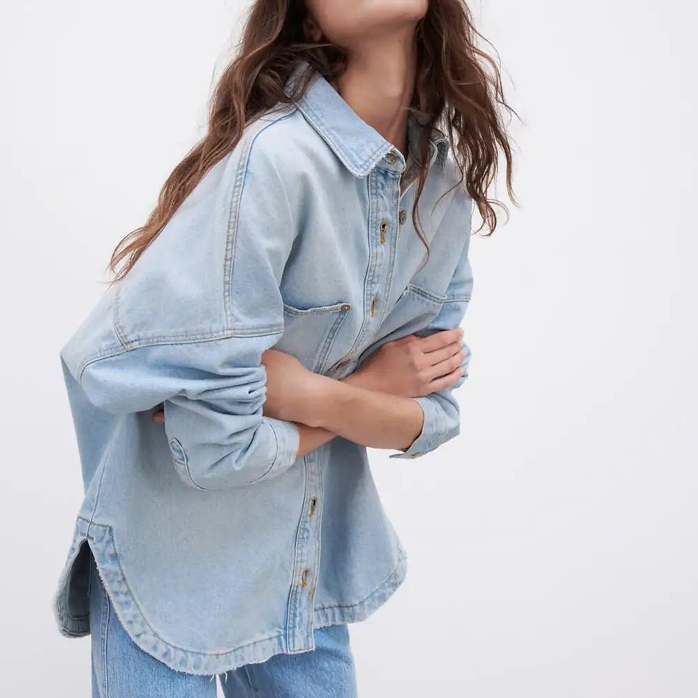 Side angle of light blue denim shirt jacket worn with sleeves rolled up.
