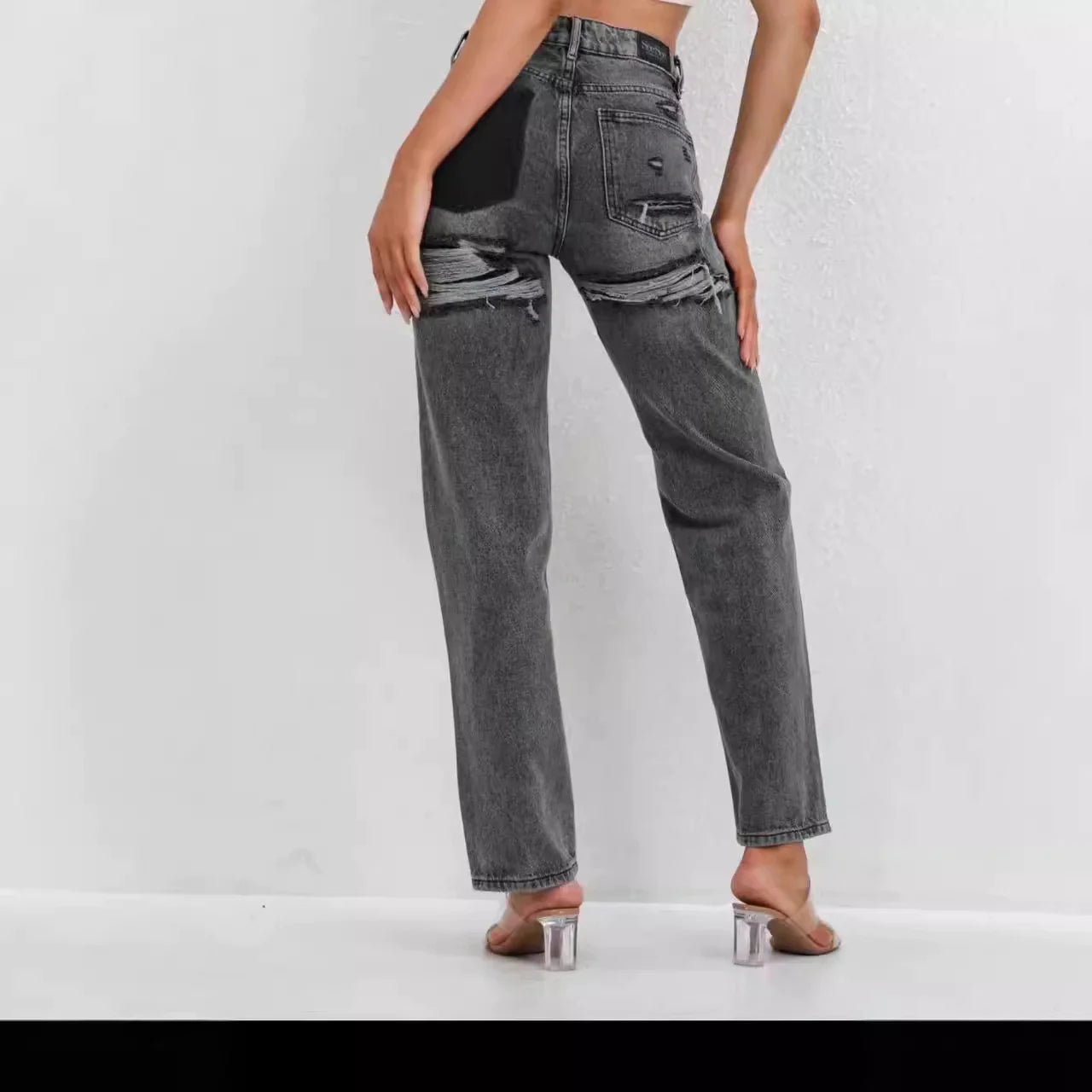High-waisted gray distressed straight leg jeans with raw hem, styled with heeled sandals