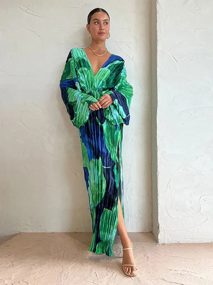 "Elegant long-sleeve pleated maxi dress with a bold green and blue abstract floral print, featuring a deep V-neckline and relaxed fit."