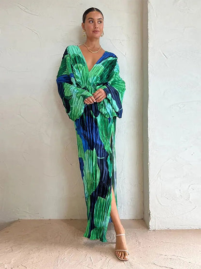 "Elegant long-sleeve pleated maxi dress with a bold green and blue abstract floral print, featuring a deep V-neckline and relaxed fit."