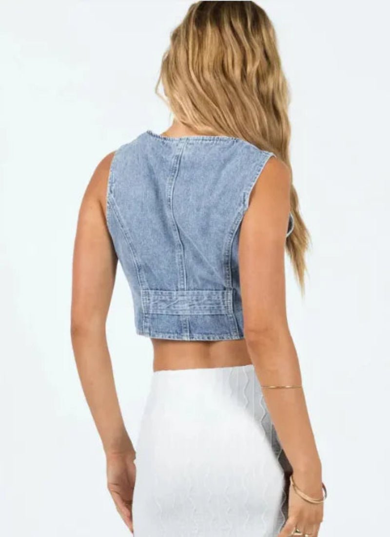 "Back view of a woman wearing a cropped denim vest, highlighting the design and stitching details, paired with casual accessories."

