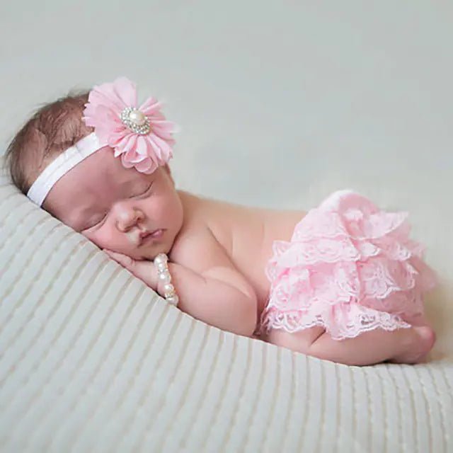 "Cute newborn baby in pink lace bloomers with flower headband and pearl bracelet".

