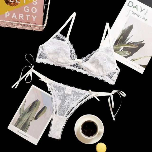 Flat lay of a white lace sleepwear set on a black background with lifestyle elements