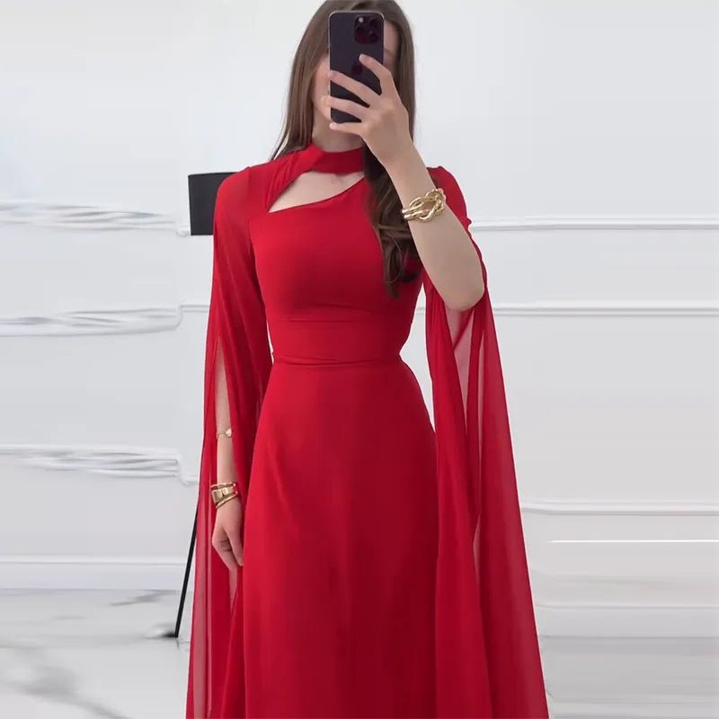 Elegant red formal long dress with dramatic cape sleeves and a cutout neckline, worn with gold accessories.