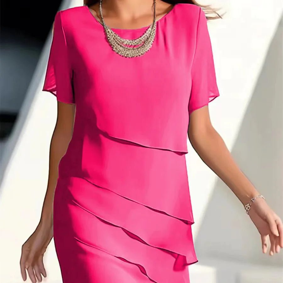Women's elegant chiffon patchwork dress in bright pink, featuring short sleeves and layered design, accessorized with a silver necklace.