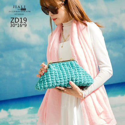 Two pleated handbags (green and pink) shown in hand with beach background.
