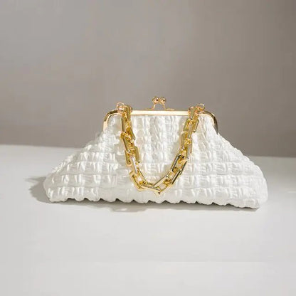 White pleated handbag displayed lying flat on a plain surface.