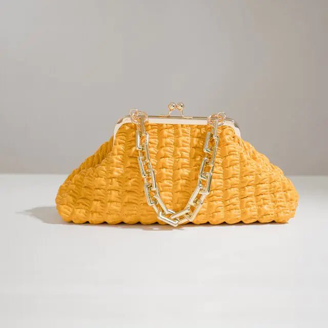 Yellow pleated handbag with gold chain on a plain background.