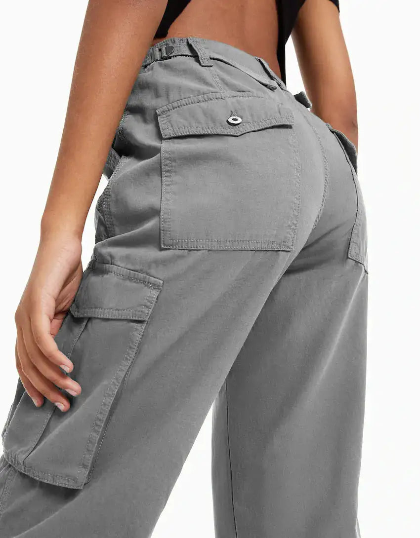 Close-up back view of gray utility trousers with buttoned back pockets and roomy fit.