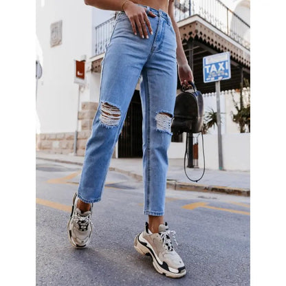 High-waisted ripped jeans in classic blue, styled with sneakers and a crop top, captured outdoors for a casual urban look.