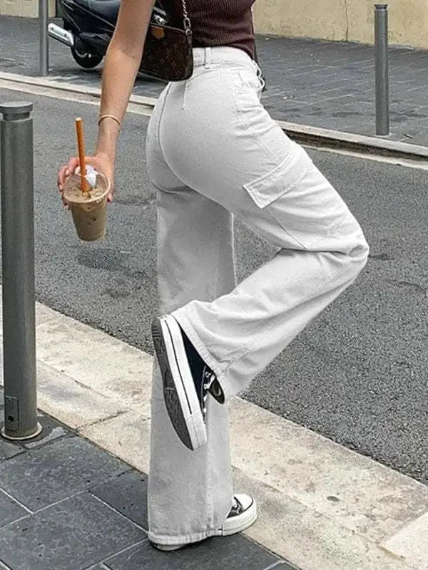 Close-up side view of a woman in light gray cargo pants, showing pocket details while holding iced coffee on the sidewalk.