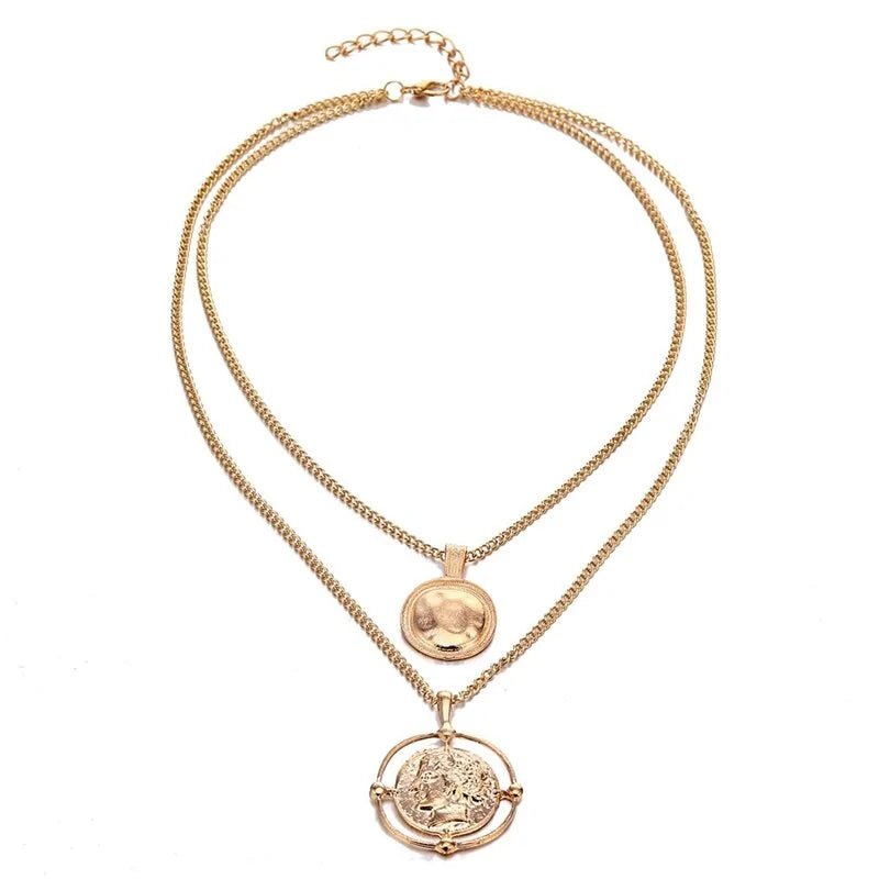 Full view of the gold double-chain necklace with round and carved coin pendants, laid flat on a white background.