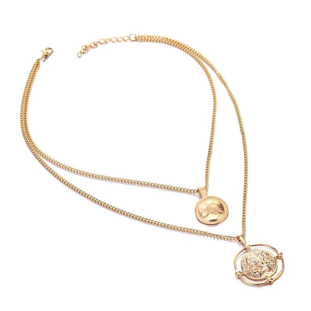 Full view of the gold double-chain necklace with round and carved coin pendants, laid flat on a white background.
