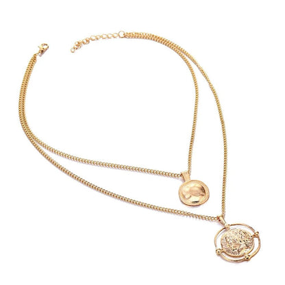 Full view of the gold double-chain necklace with round and carved coin pendants, laid flat on a white background.