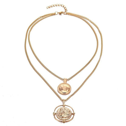 Full view of the gold double-chain necklace with round and carved coin pendants, laid flat on a white background.