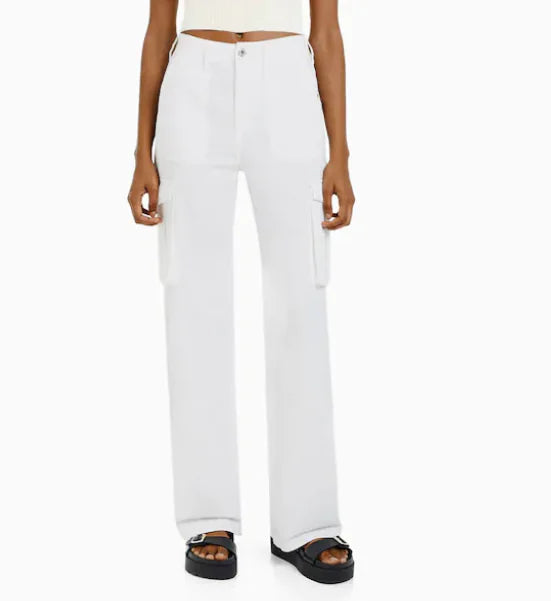 Front view of white utility cargo trousers with large side pockets and high-waist fit, worn with platform sandals.